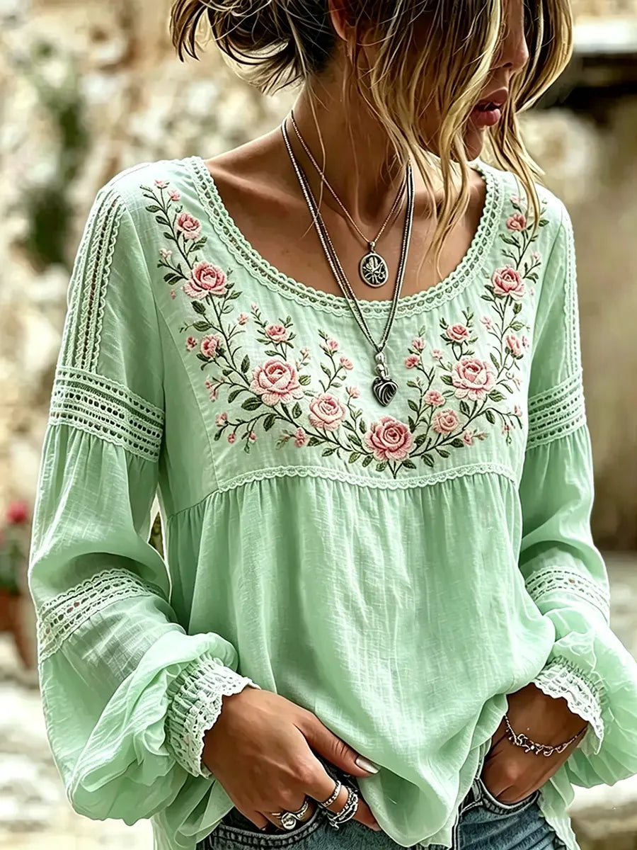 Green blouse with rose embroidery, a rounded neckline and lace-trimmed sleeves