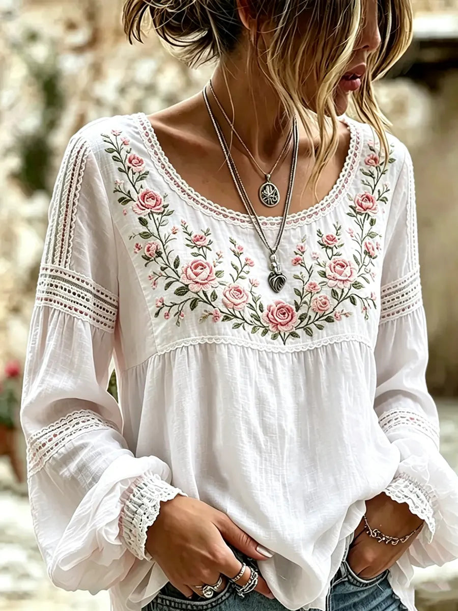 White blouse with rose embroidery, a rounded neckline and lace-trimmed sleeves