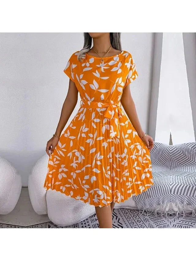 Woman wearing an orange white-leaf-print midi dress with pleated skirt and waist tie