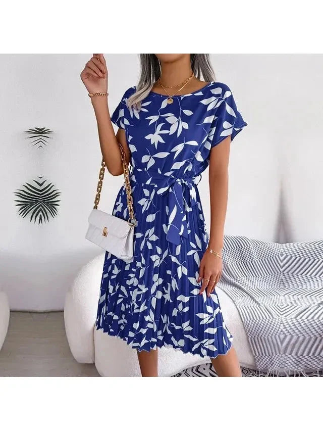 Woman wearing a royal-blue white-leaf-print midi dress with pleated skirt and waist tie