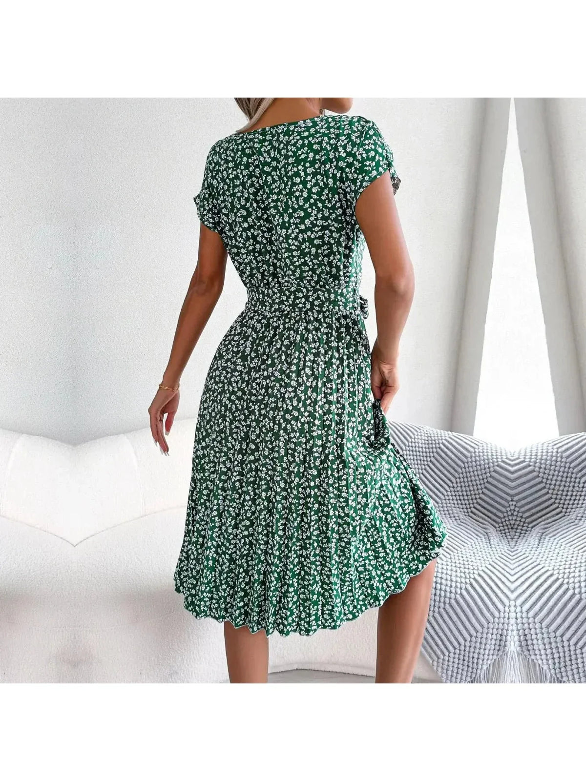 Back view of a green floral midi dress with pleated skirt and waist tie