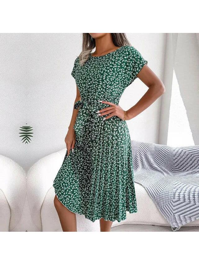 Woman wearing a green floral midi dress with pleated skirt and waist tie, side view