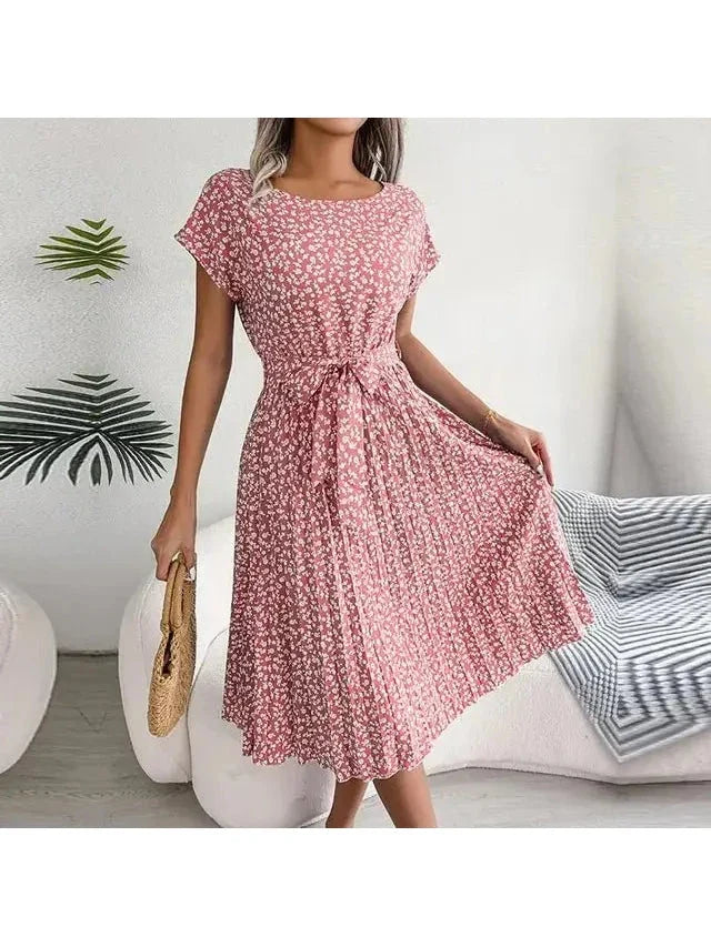 Woman wearing a pink floral midi dress with pleated skirt and waist tie, front view