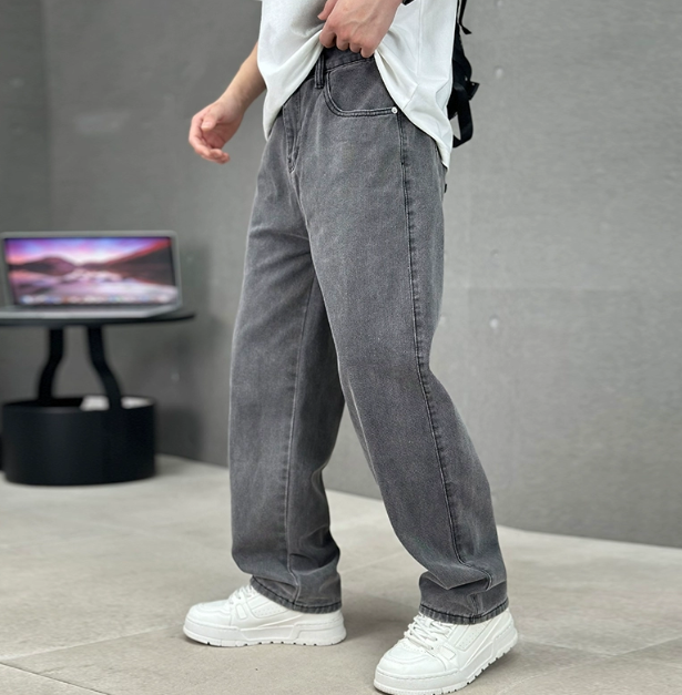Man wearing loose grey straight-leg jeans with white trainers