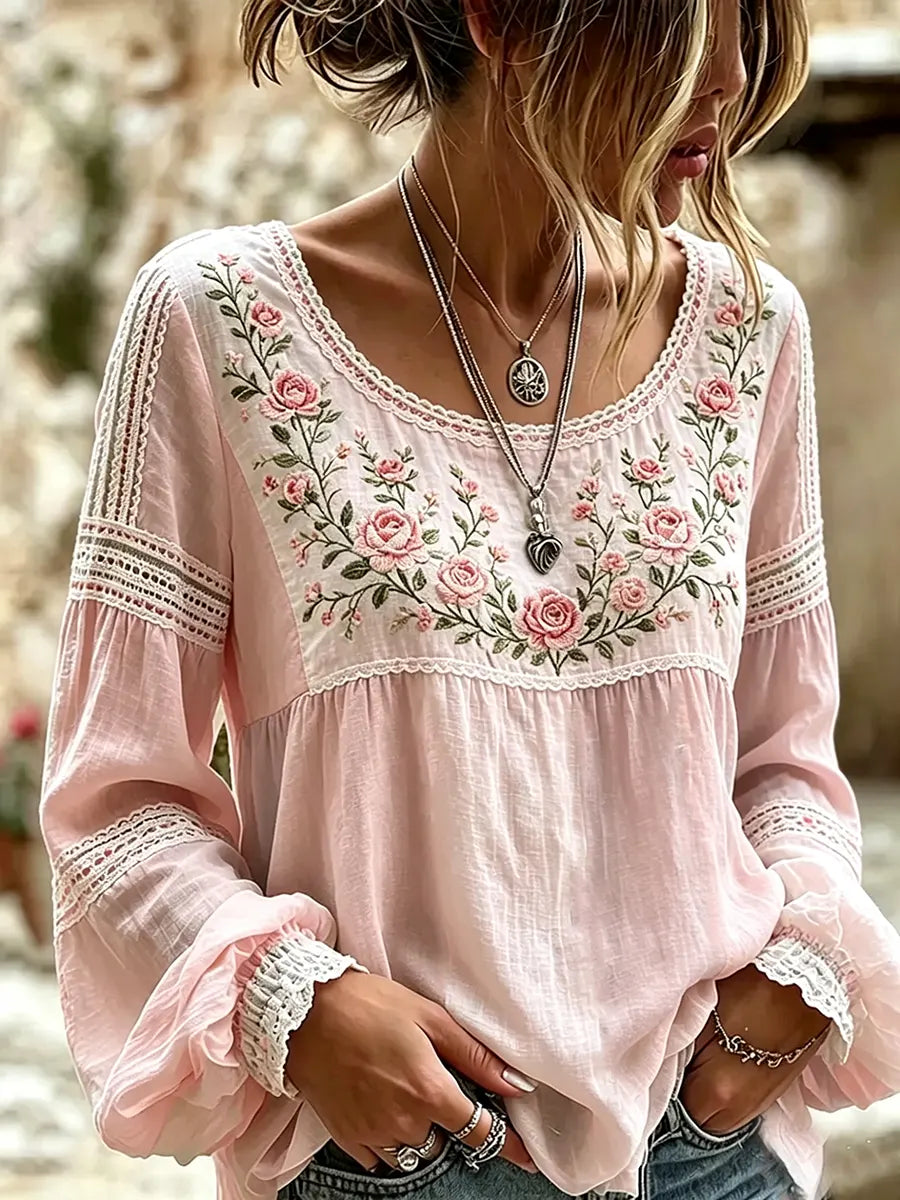 Pink blouse with rose embroidery, a rounded neckline and lace-trimmed sleeves