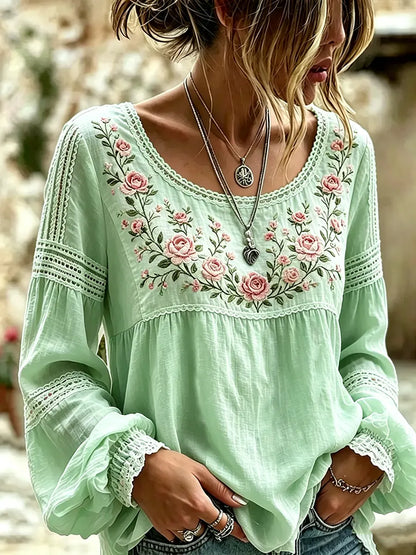 Green blouse with rose embroidery, a rounded neckline and lace-trimmed sleeves
