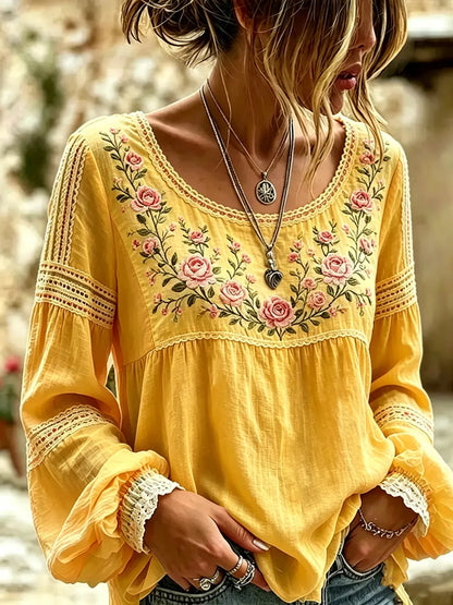Yellow blouse with rose embroidery, a rounded neckline and lace-trimmed sleeves