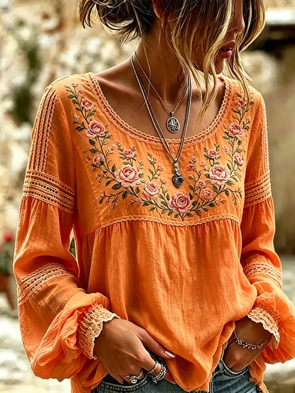 Orange blouse with rose embroidery, a rounded neckline and lace-trimmed sleeves