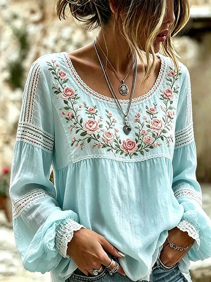 Light Blue blouse with rose embroidery, a rounded neckline and lace-trimmed sleeves