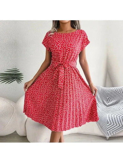 Woman wearing a coral-red small-floral midi dress with pleated skirt and waist tie