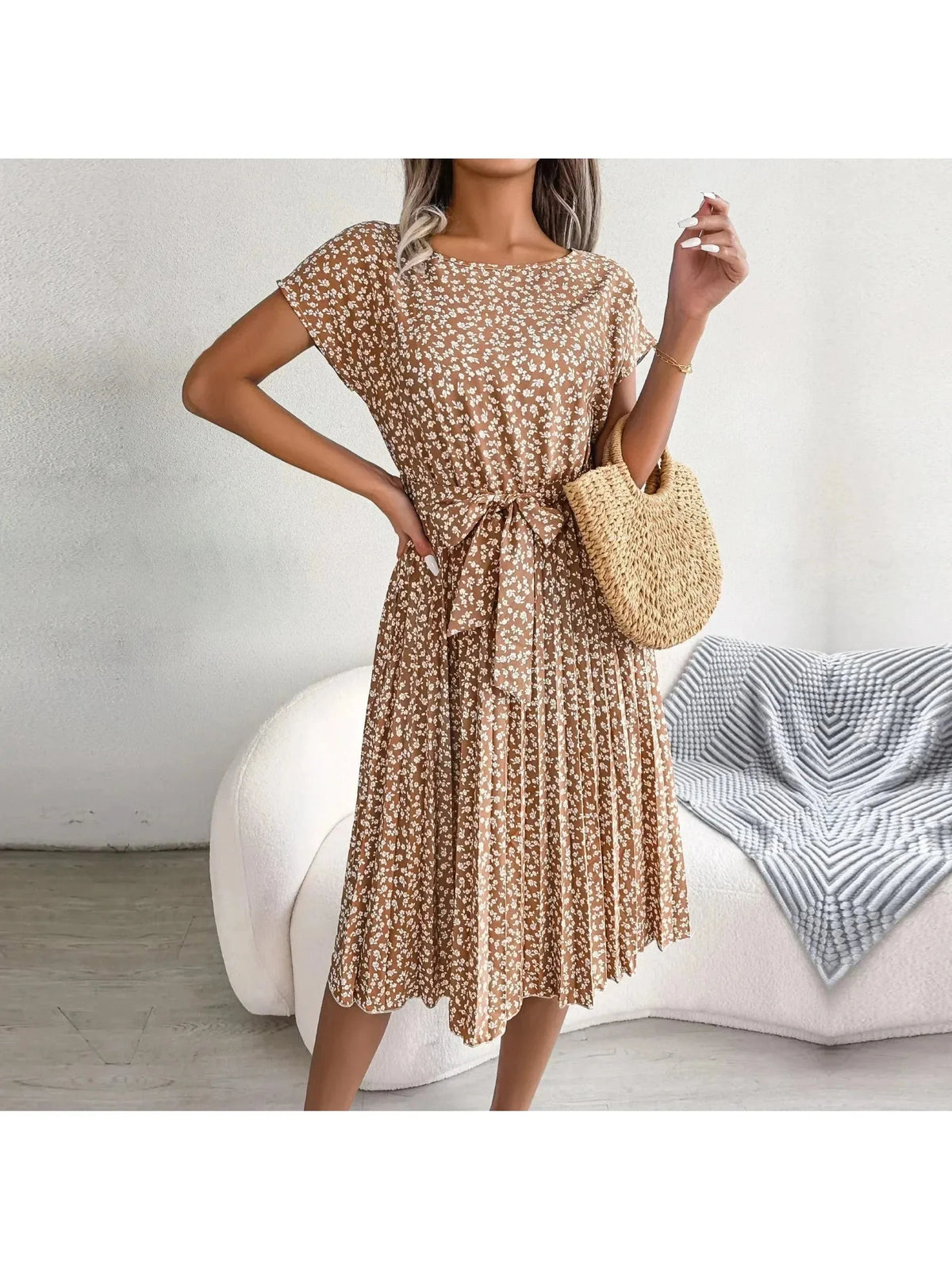 Woman wearing a light-brown floral midi dress with pleated skirt and waist tie