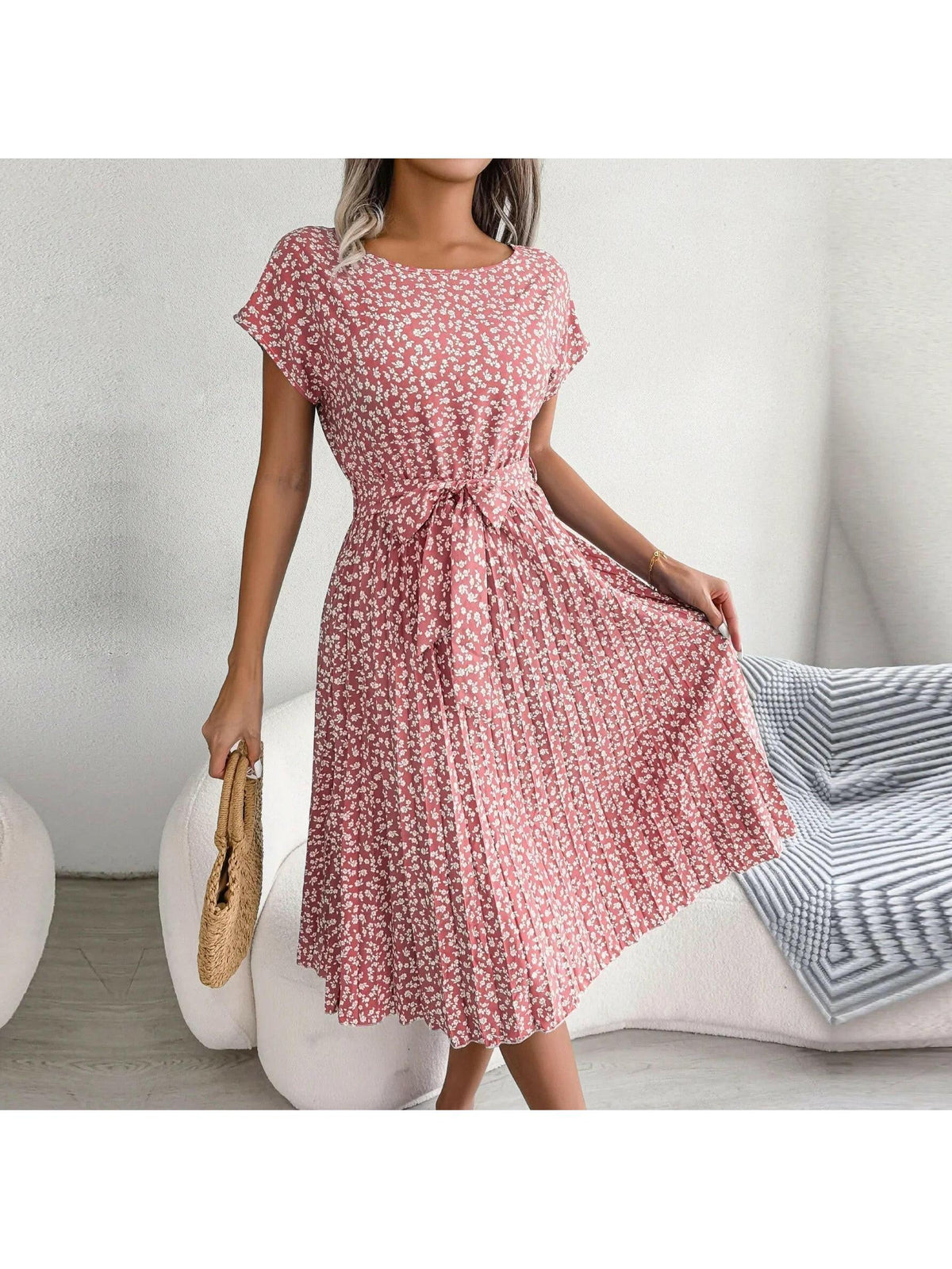 Woman wearing a pink floral midi dress with pleated skirt and waist tie