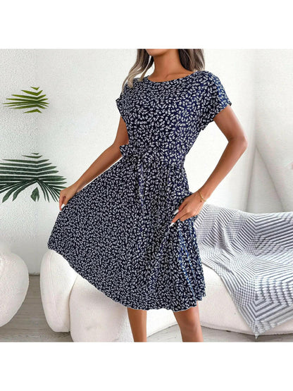 Woman wearing a dark-blue small-floral midi dress with pleated skirt and waist tie