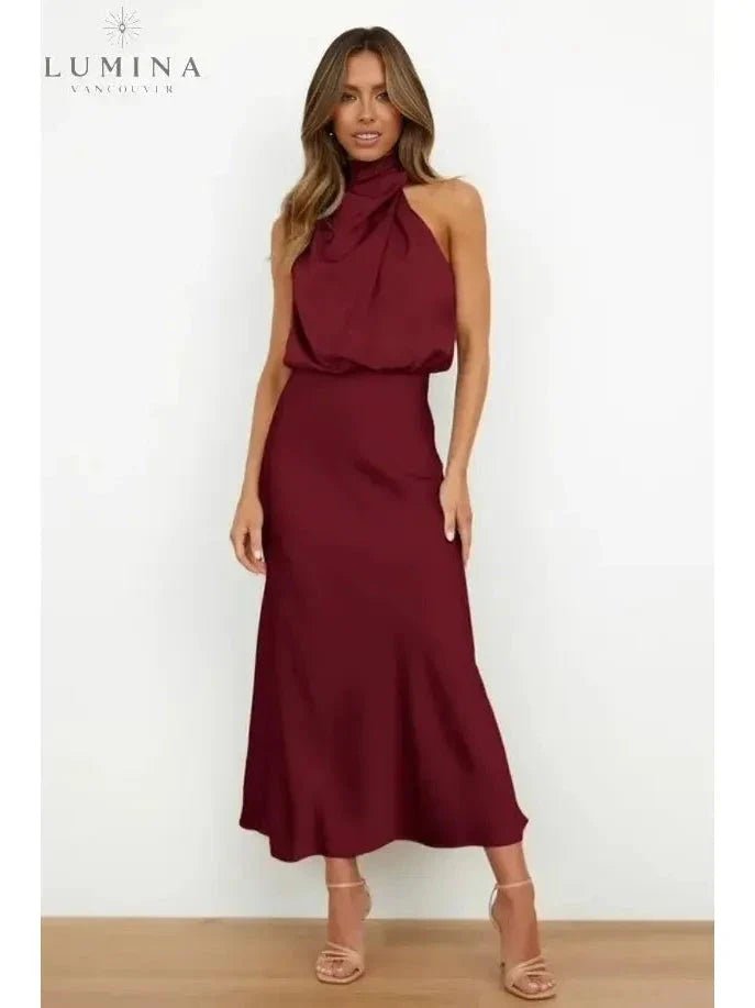 Woman wearing a burgundy-red draped halter-neck midi dress, front view