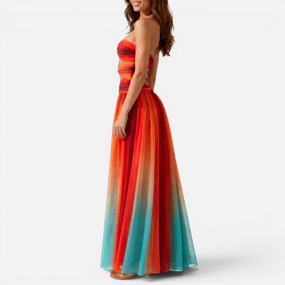 Woman wearing a strapless red-and-orange ombré maxi dress with waist cut-outs, side view