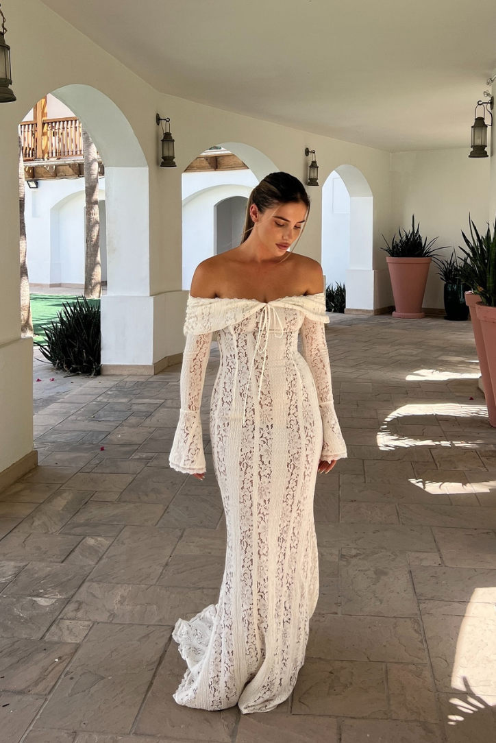 Woman wearing a white off-shoulder lace maxi dress with fluted sleeves, full front view outdoors
