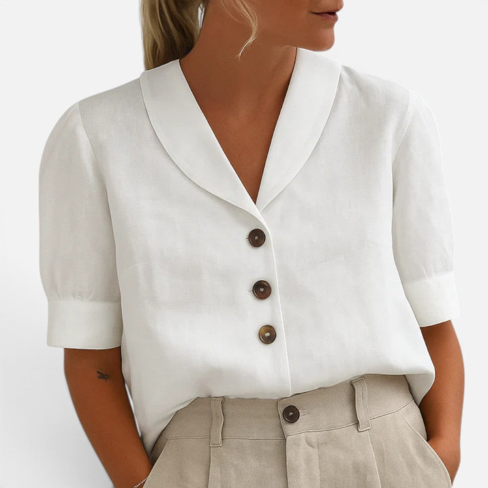 Woman wearing a navy short-sleeve blouse with a V-shaped collar and three-button front