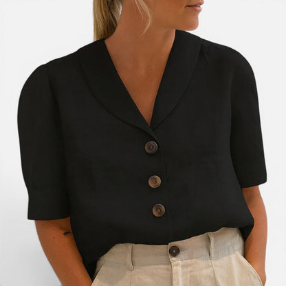Woman wearing a black short-sleeve blouse with a V-shaped collar and three-button front