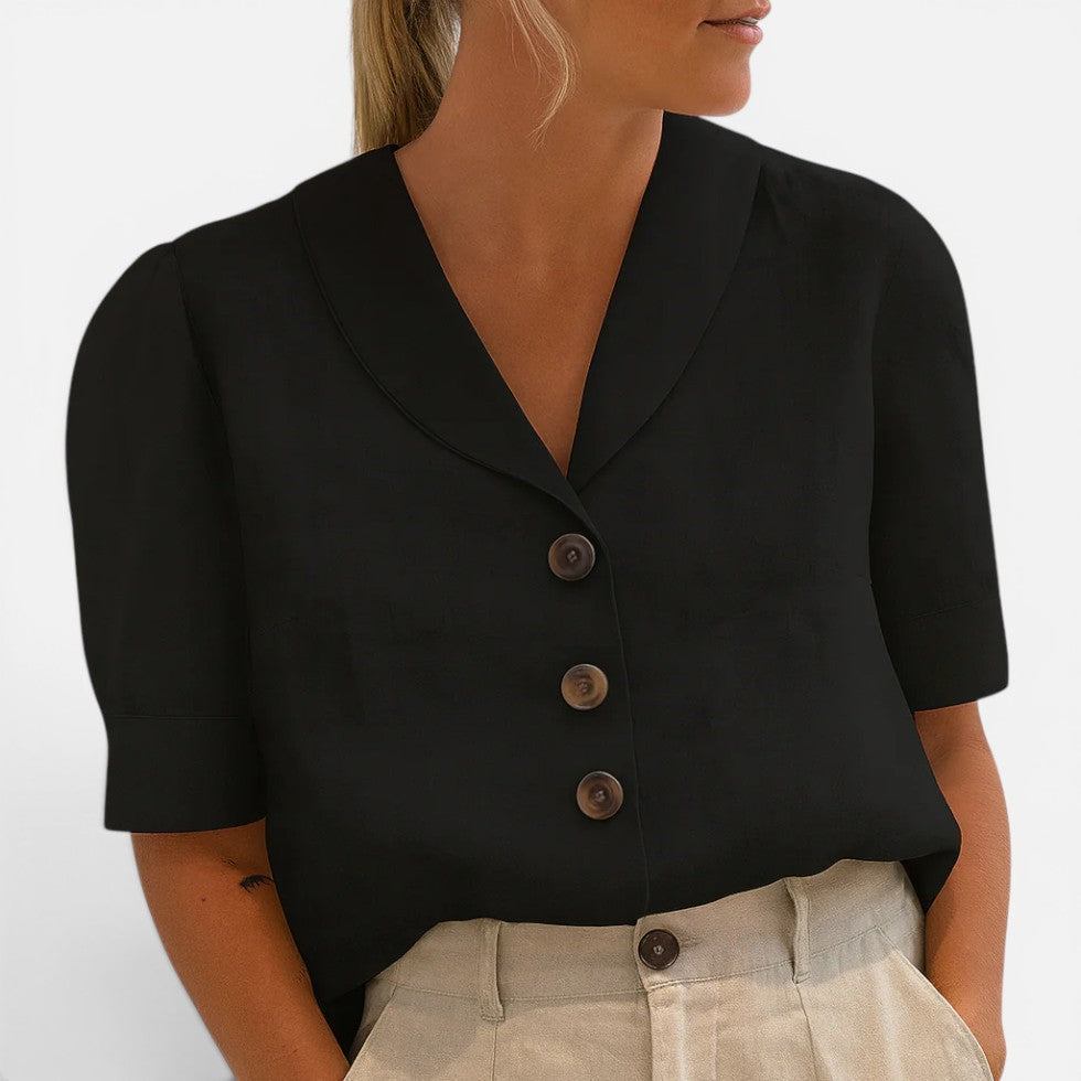 Woman wearing a black short-sleeve blouse with a V-shaped collar and three-button front