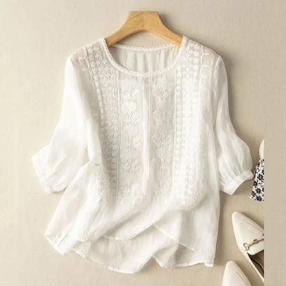 Front view of a white blouse with raised floral motifs on the front panels
