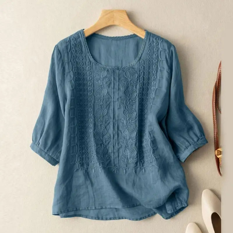 Front view of a blue blouse with raised floral motifs on the front panels