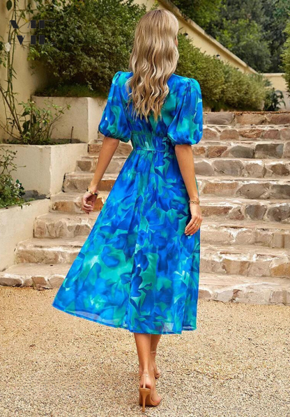 Woman wearing a blue-and-teal abstract floral V-neck midi dress, rear view